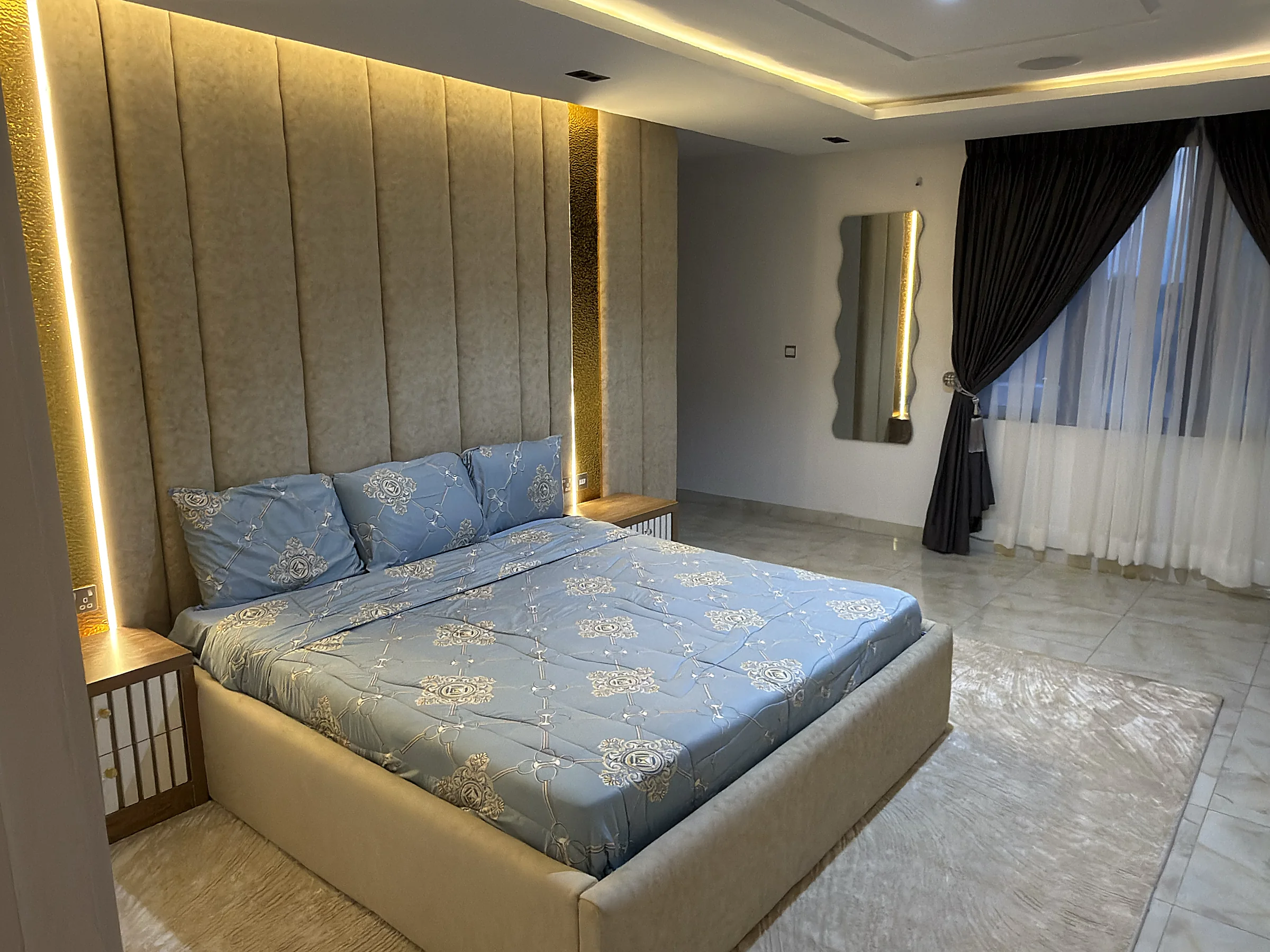 Primary bedroom with a padded feature wall and integrated warm lighting