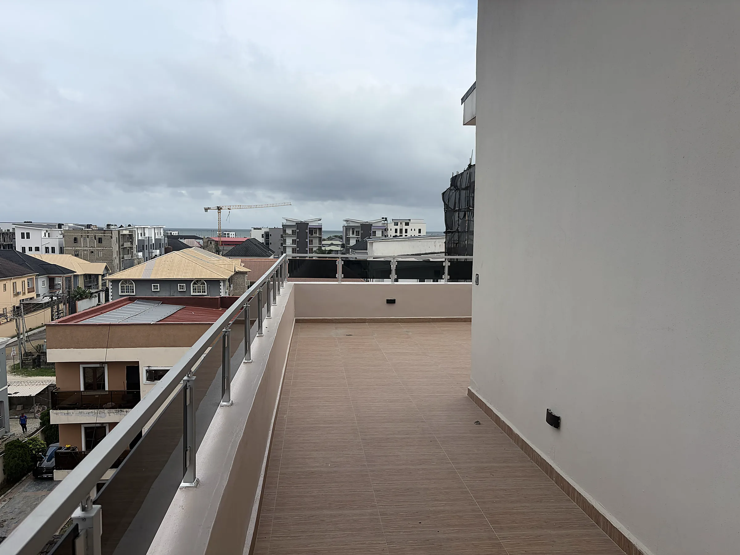 The upper terrace at Canary Penthouse, with a glass balustrade and a view across Ilasan toward the coast